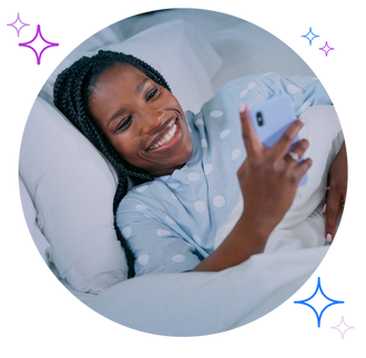 Woman in pajamas looking at phone while tucked in bed