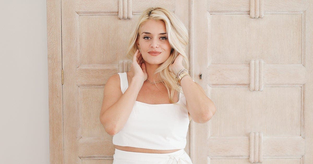 Daphne Oz’s in white attire posing elegantly in a brightly lit room.