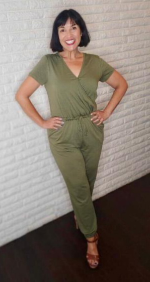 WW member Elsa, a woman with short brown hair with bands, wearing a green jumpsuit.