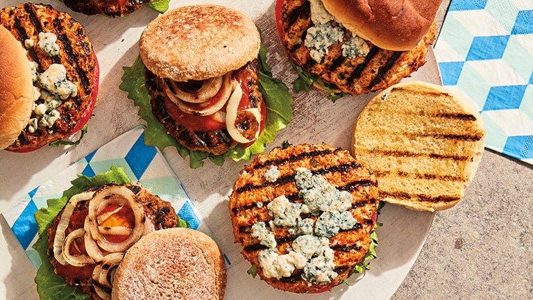 4 burger patties cooking on an outdoor grill