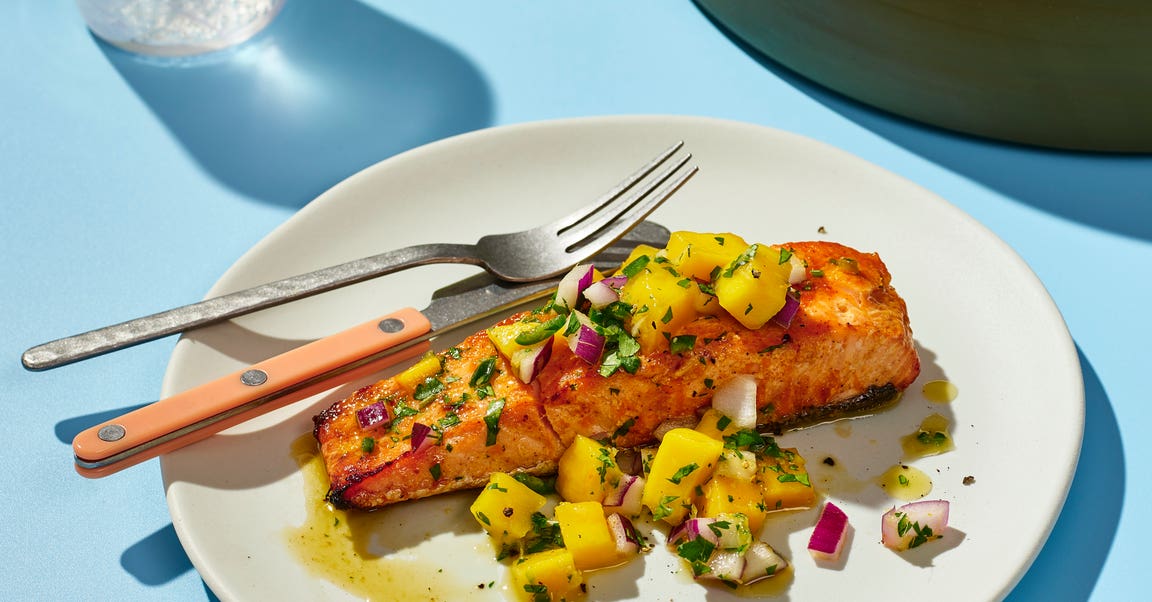 Plate with a piece of salmon covered in mango salsa on a dinner table