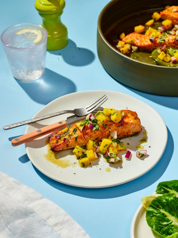 Plate with a piece of salmon covered in mango salsa on a dinner table