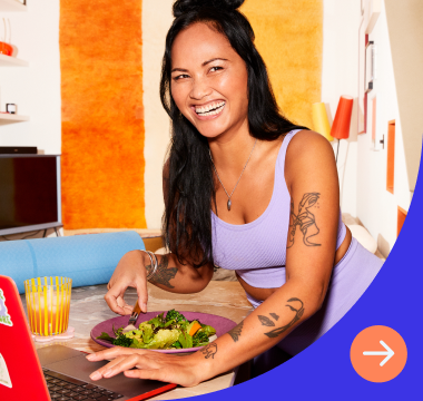 Woman smiles while eating and working on computer