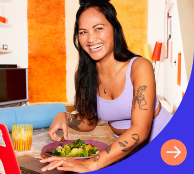 Woman smiles while eating and working on computer