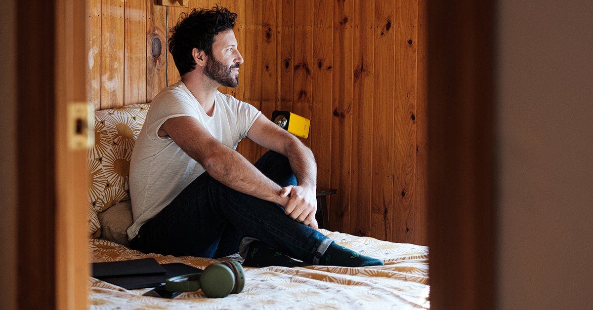 man with diabetes sitting in bed with laptop and earphones
