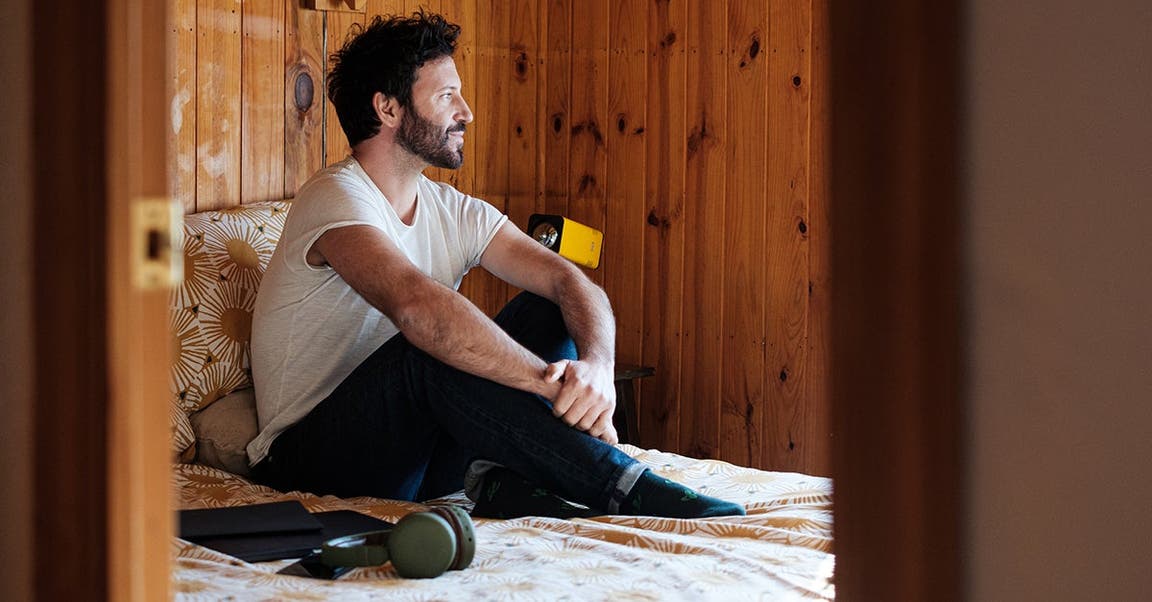 man with diabetes sitting in bed with laptop and earphones