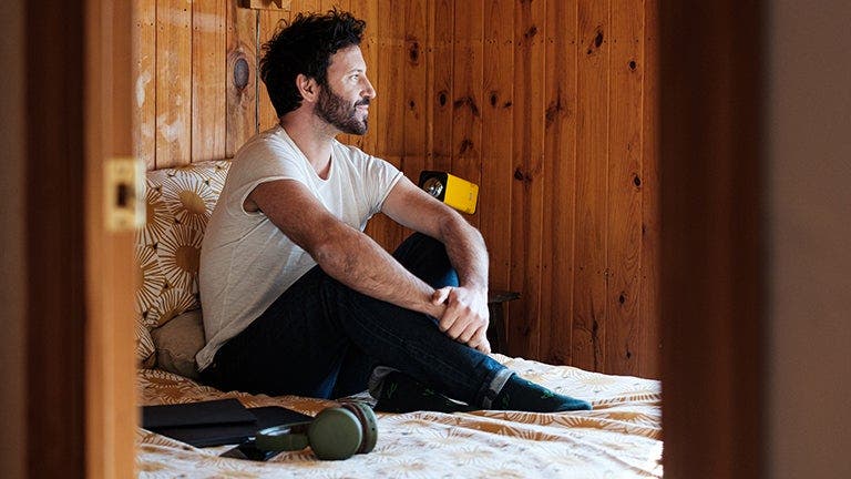 man with diabetes sitting in bed with laptop and earphones