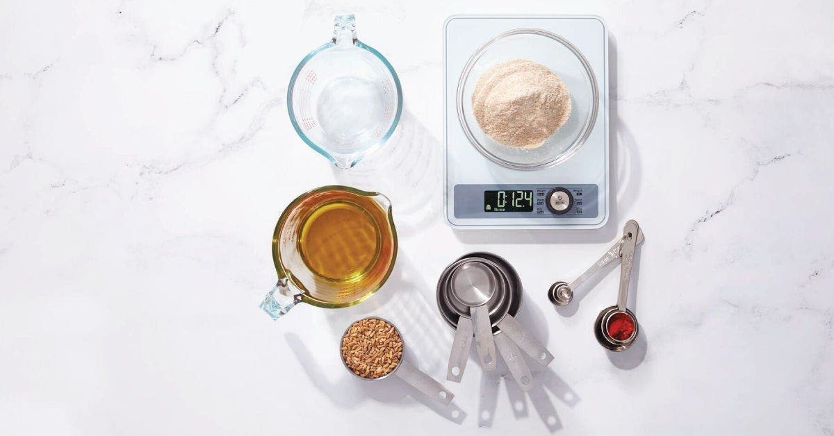 Assorted baking ingredients neatly arranged on a scale, including flour, sugar, eggs, and butter.