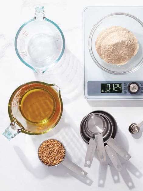 Assorted baking ingredients neatly arranged on a scale, including flour, sugar, eggs, and butter.
