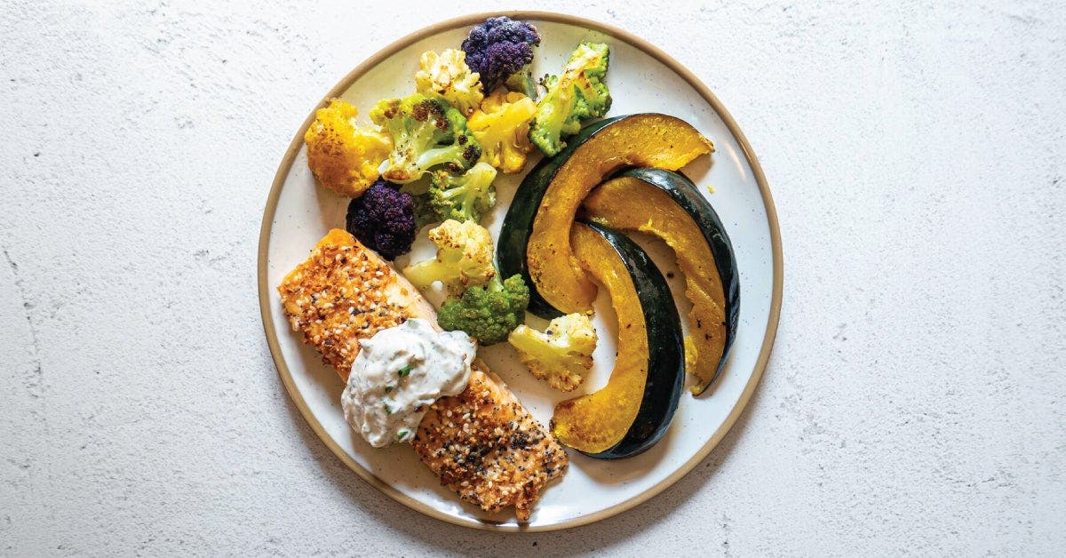 A plate of salmon, vegetables, and a side dish.