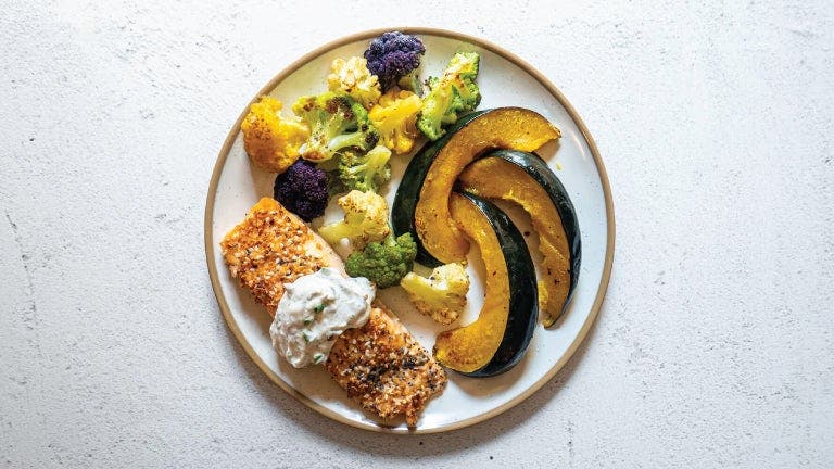 A plate of salmon, vegetables, and a side dish.