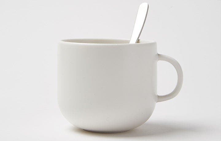 Empty white ceramic mug with a silver spoon resting inside