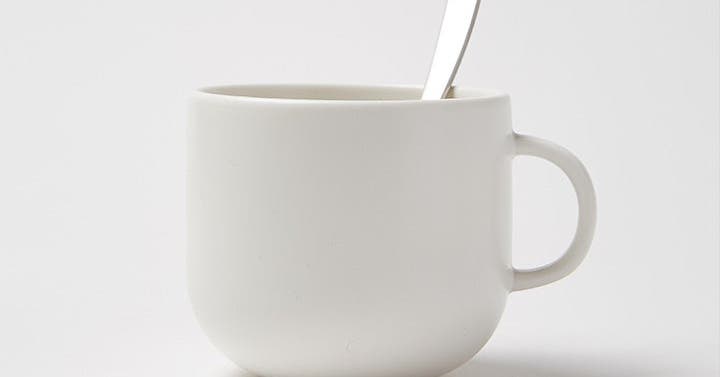 Empty white ceramic mug with a silver spoon resting inside