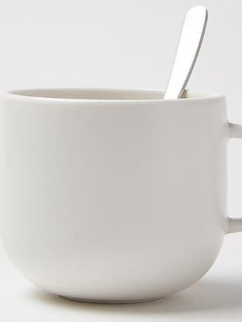 Empty white ceramic mug with a silver spoon resting inside