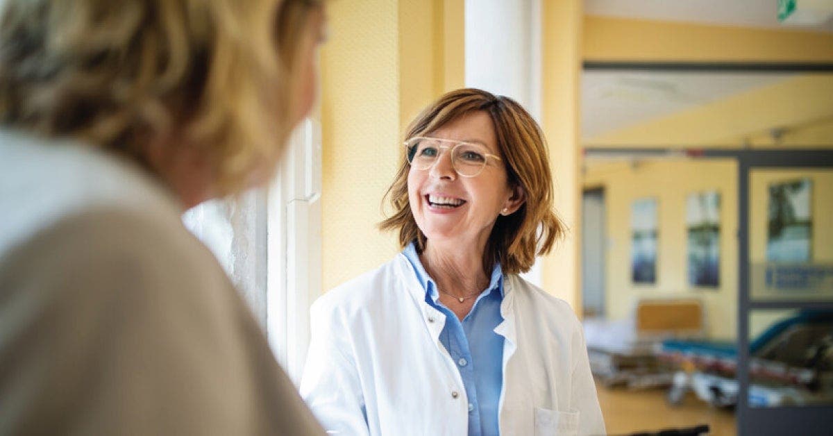 A woman in a white coat conversing with another woman.