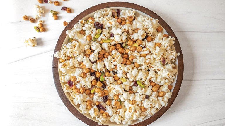  A bowl of popcorn with nuts on a white table.