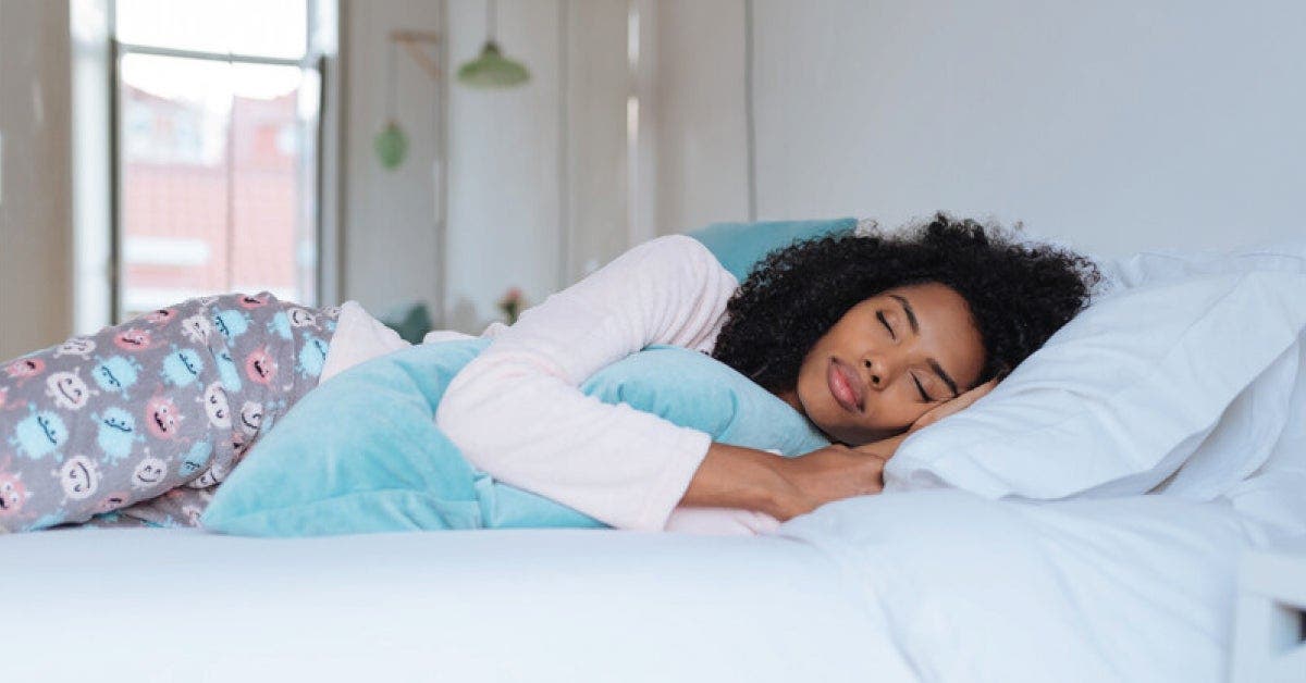 An image of a woman resting on a bed with a pillow.