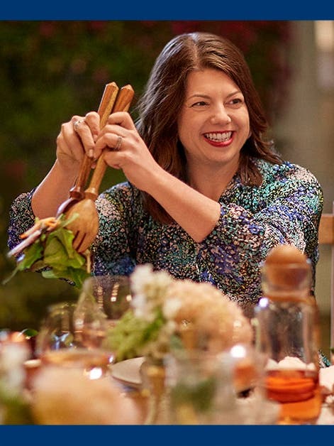 WW member Brigid G. serving a salad and smiling at a dinner table