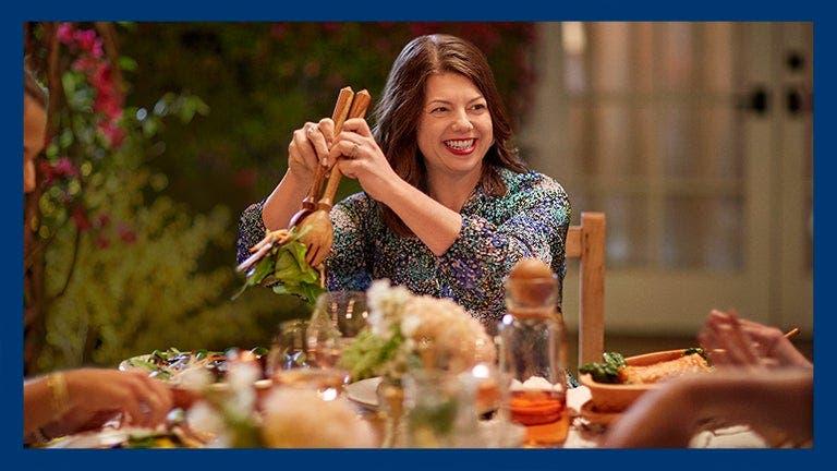 WW member Brigid G. serving a salad and smiling at a dinner table