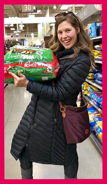 Cari posing with a bag of dog food in the grocery store