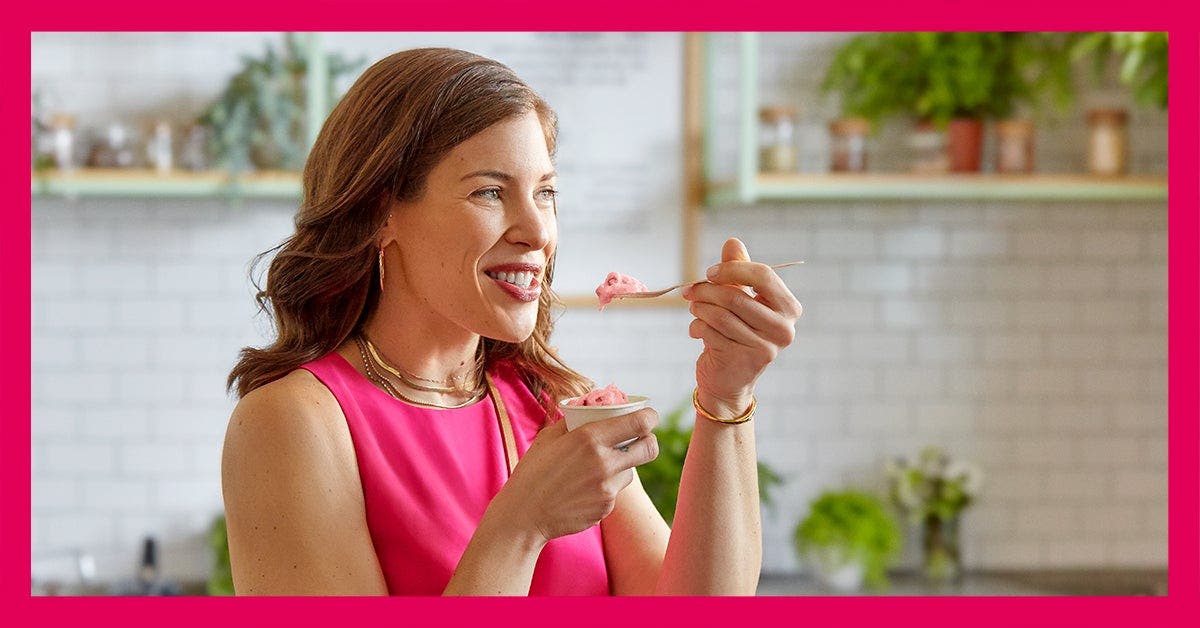 WW Coach, Cari, eating and smiling in the kitchen