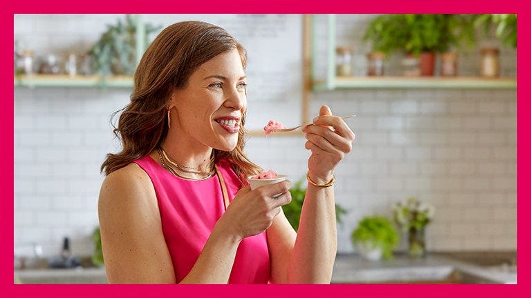 WW Coach, Cari, eating and smiling in the kitchen
