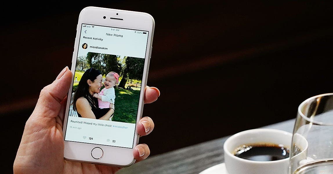 A woman holds a phone showing a Connect post in the WW app.