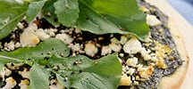 Pizza au fromage de chèvre, à la roquette et au basilic