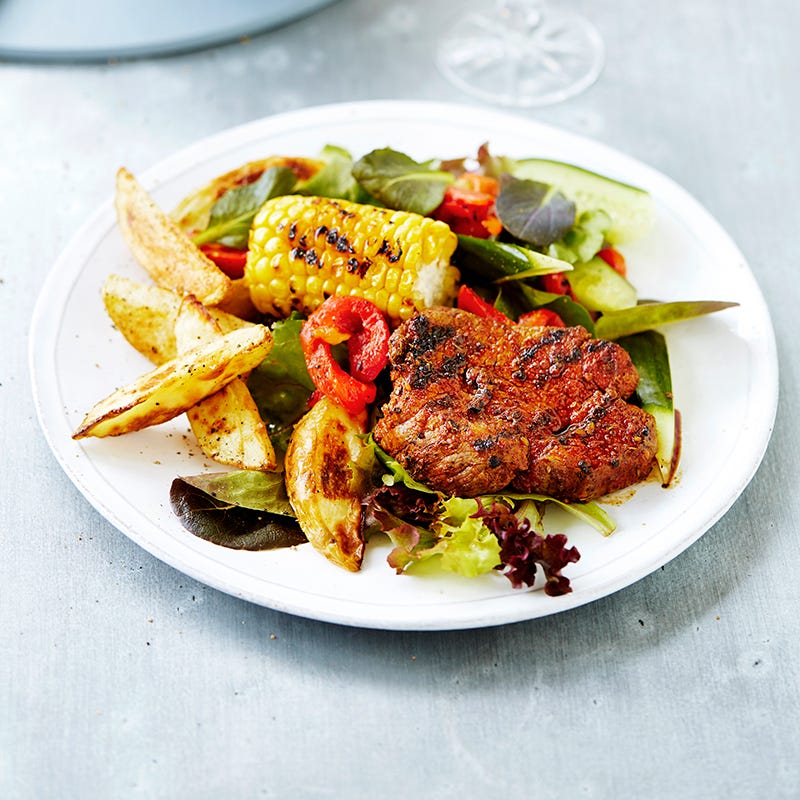 Cajun steak with potato wedges and grilled corn