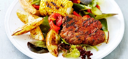 Cajun steak with potato wedges and grilled corn