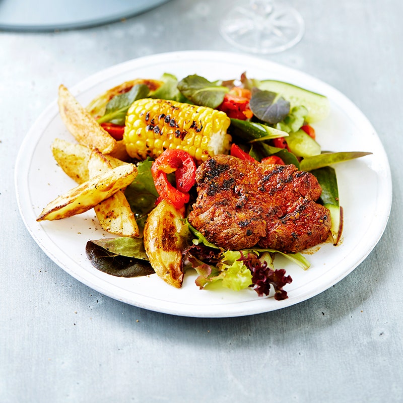 Cajun steak with potato wedges and grilled corn