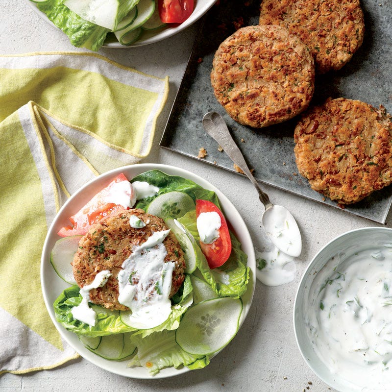 pinto bean burgers served over a lettuce, cucumber, and tomato salad, drizzled with a creamy cilantro-lime dressing