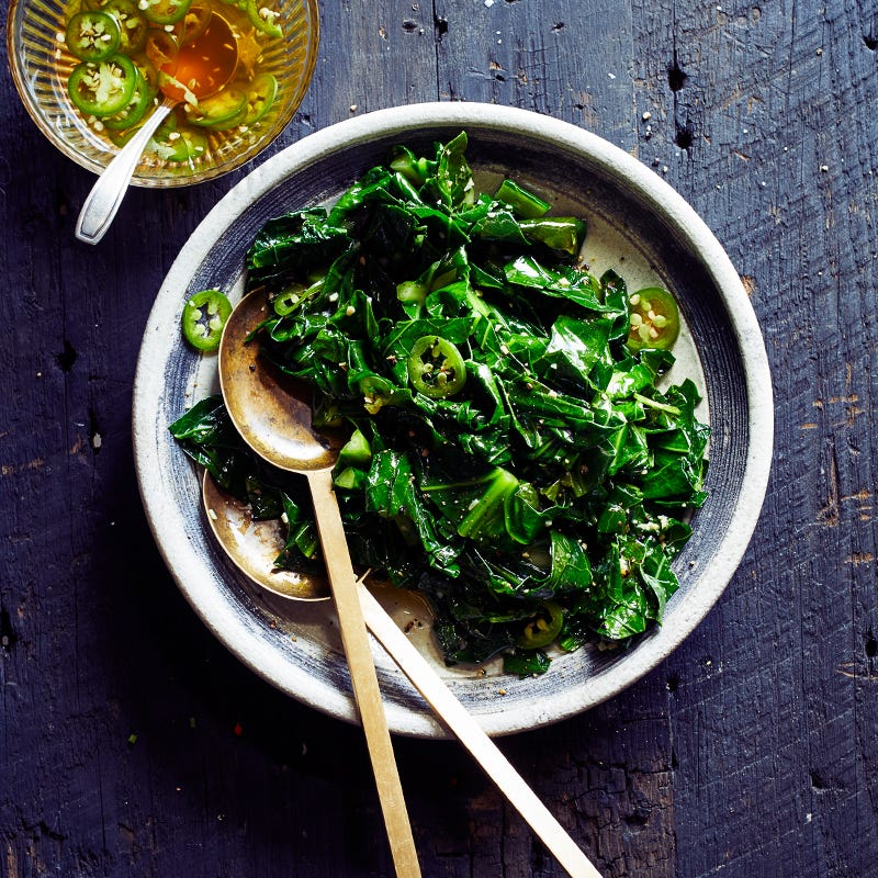 Circular serving platter topped with grilled collard greens, served with a small bowl of hot pepper vinegar
