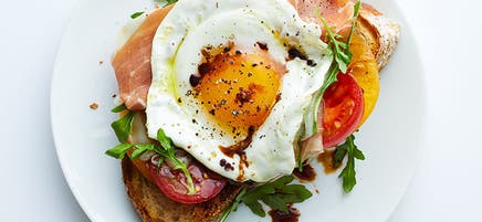 Déjeuner à l’œuf frit, au prosciutto et à la roquette sur rôtie
