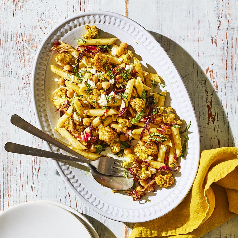 Large white oval serving platter topped with a lentil penne, chickpea, cauliflower, radicchio, feta, and mint pasta recipe