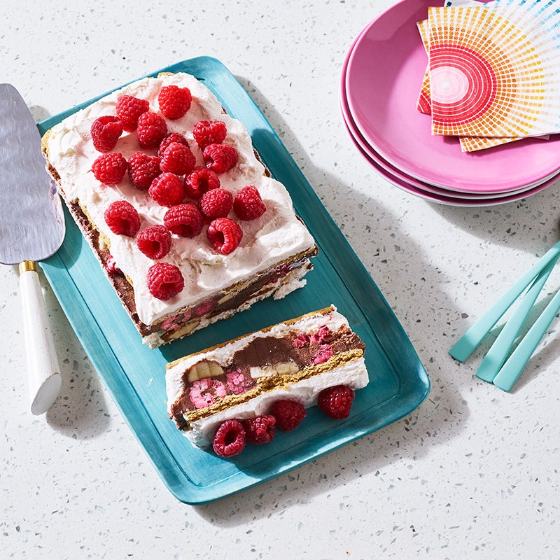 Turquoise rectangular platter topped with a layered ice cream-ice box cake garnished with fresh raspberries