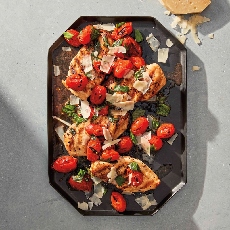 Large, gray octagonal-shaped platter topped with grilled chicken and tomatoes, garnished with a basil-vinegar and shaved Parmesan