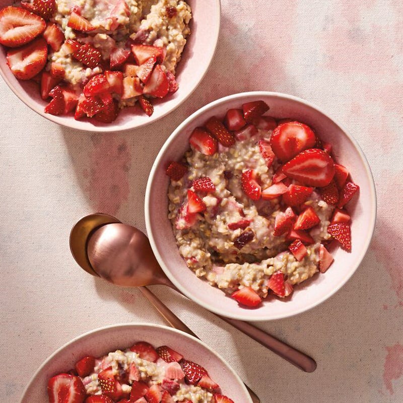 Three individual bowls of strawberry-flavored steel-cut oatmeal topped with chopped fresh strawberries